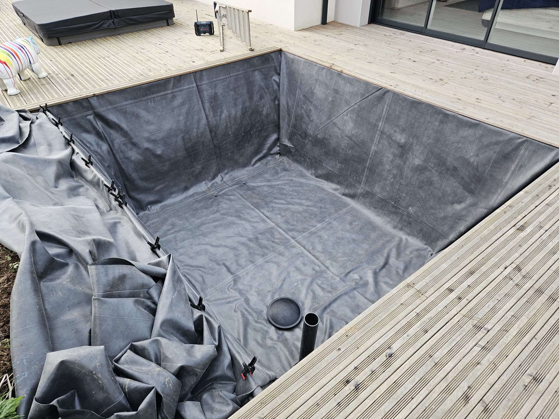La membrane EPDM noire posée dans la fosse, bonde de fond au centre