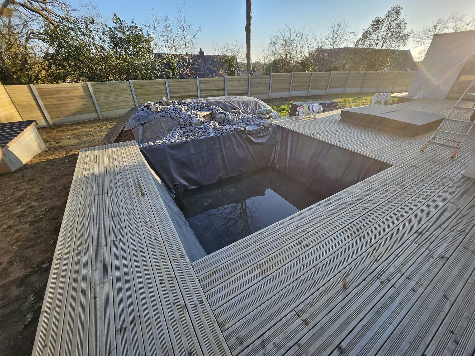 Le bassin en eau sous la terrasse, bâche de protection, ruisseau en construction — mars 2024