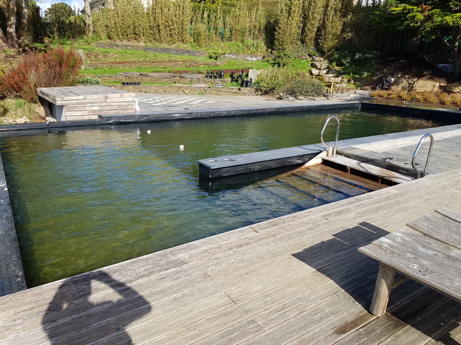 Le même point de vue une fois en eau: bassin clair, ponton fini, échelle inox