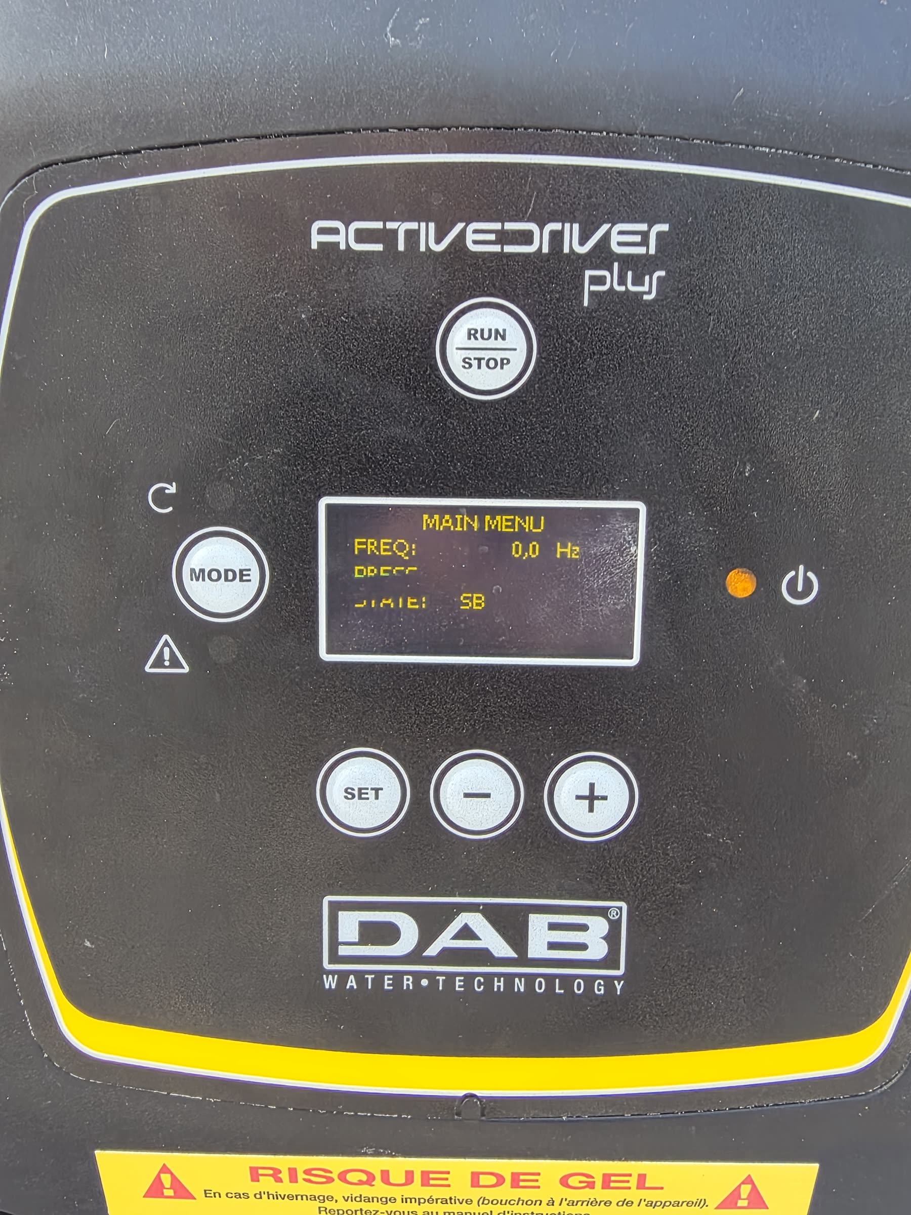 La façade du variateur DAB ActiveDriver Plus: écran allumé sur le menu principal, boutons Run/Stop, Mode, Set, plus et moins, et en bas une étiquette jaune « Risque de gel — vidange impérative »