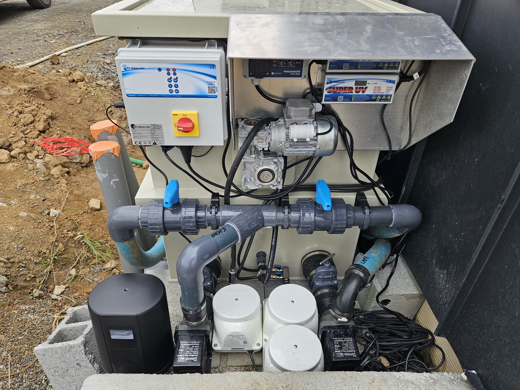 Le coffre de filtration: cuve de filtre, boîtier de commande, pompe, vannes et tuyauterie PVC gris