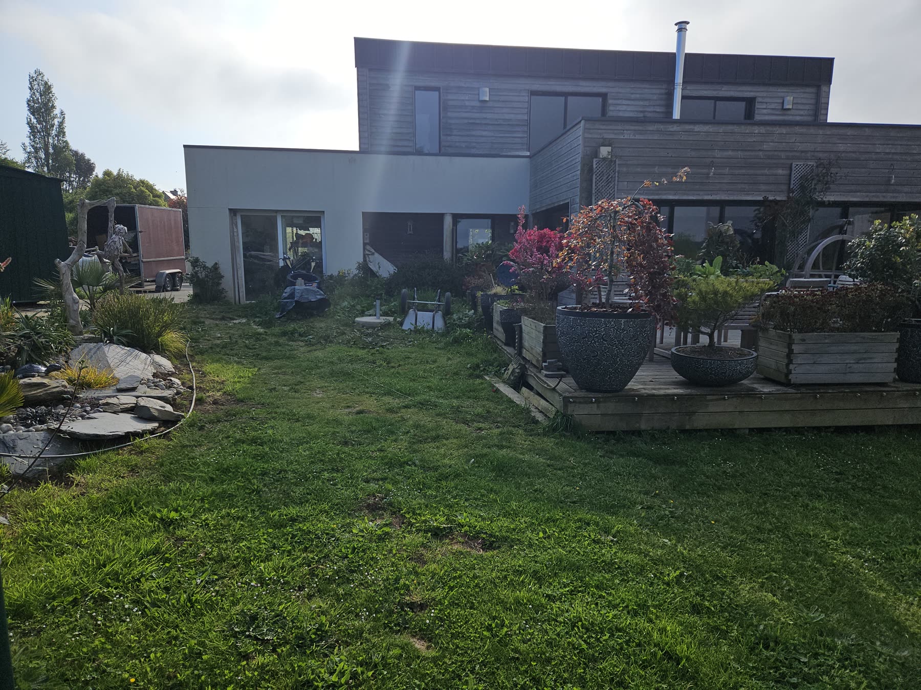 Le terrain avant: pelouse, terrasse bois, maison en bardage gris — mai 2024