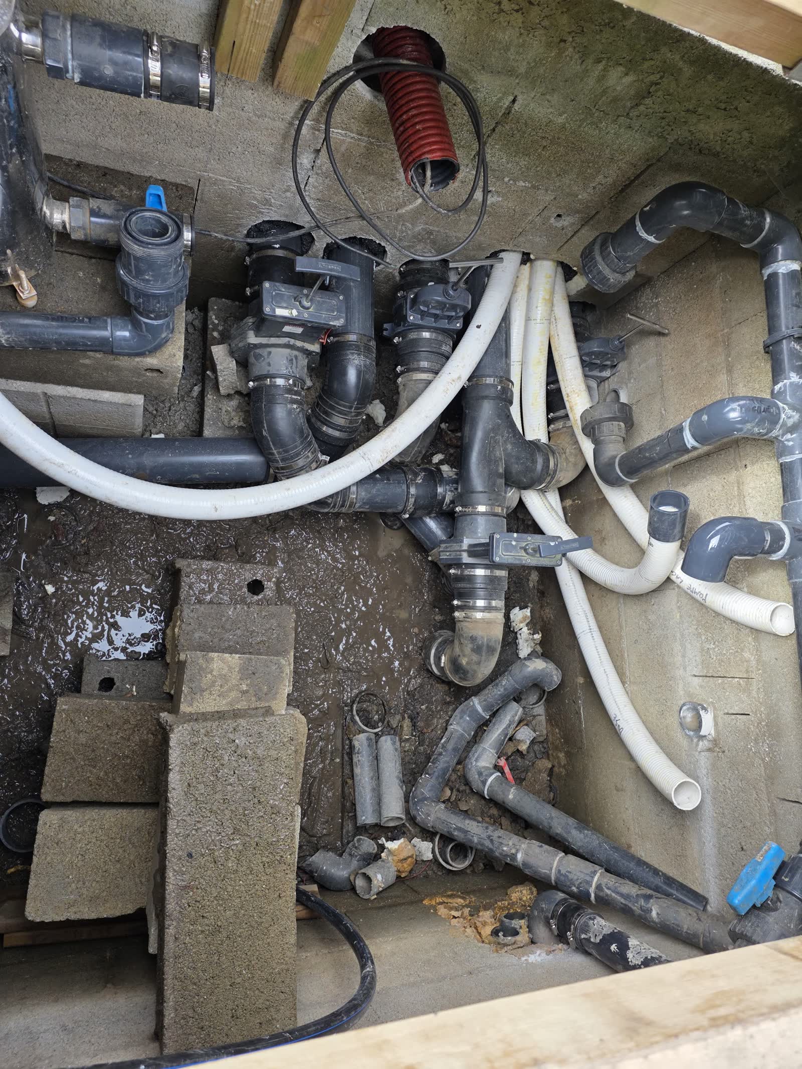 Le regard de vannes en construction: canalisations PVC, vannes, gaine rouge, en attente de raccordement