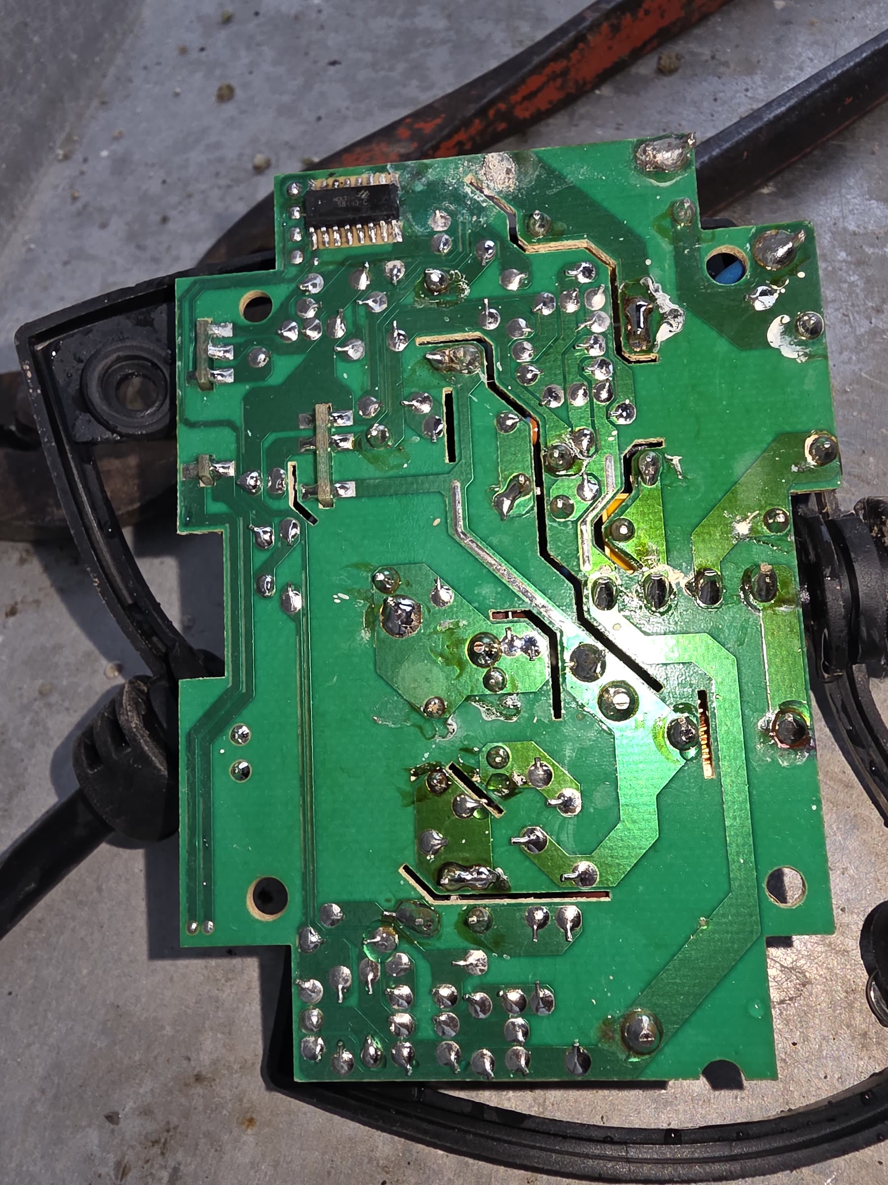 Une carte électronique verte posée sur un étau d’établi, côté soudures apparent
